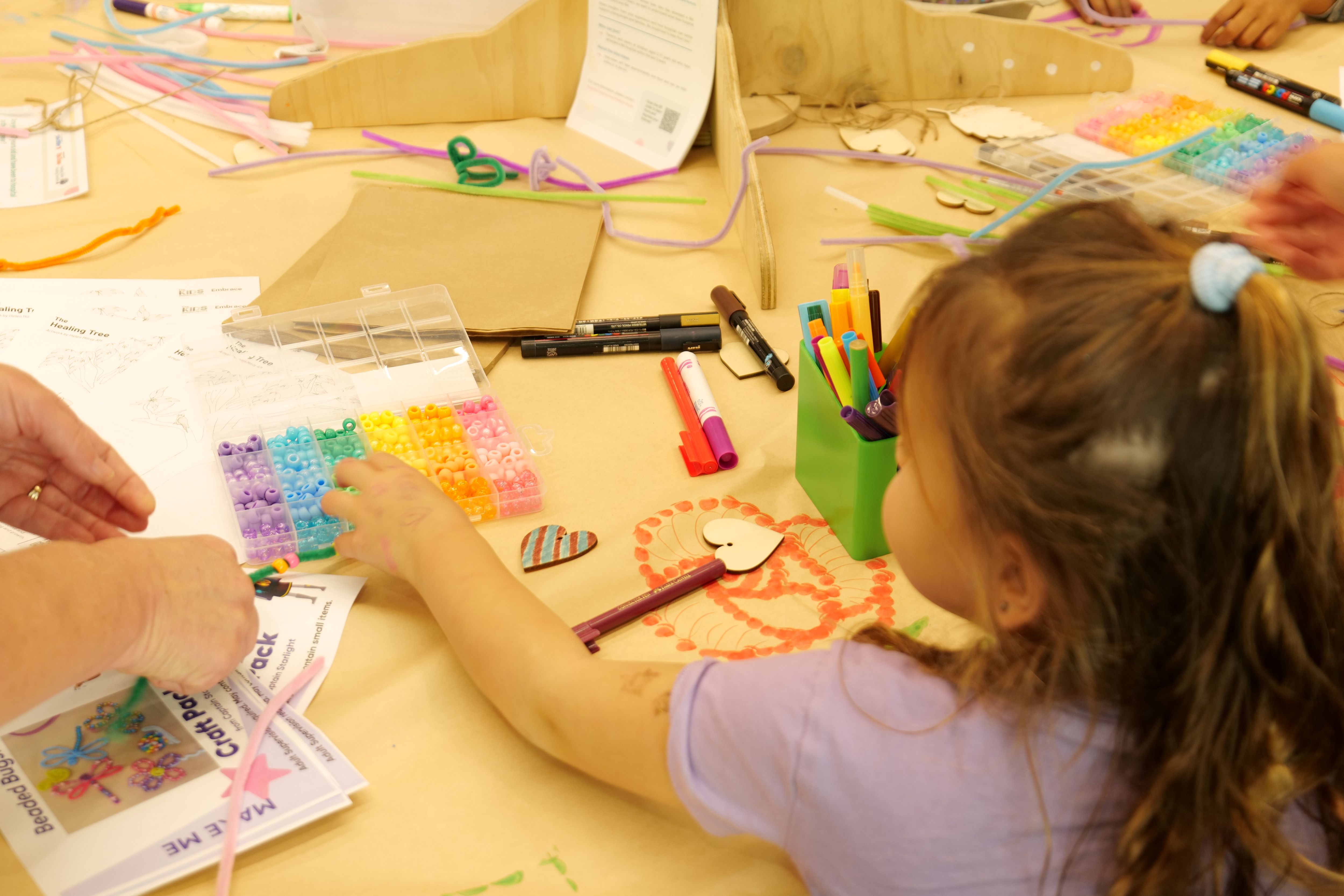 A young girl reaching for beads for a creative activity