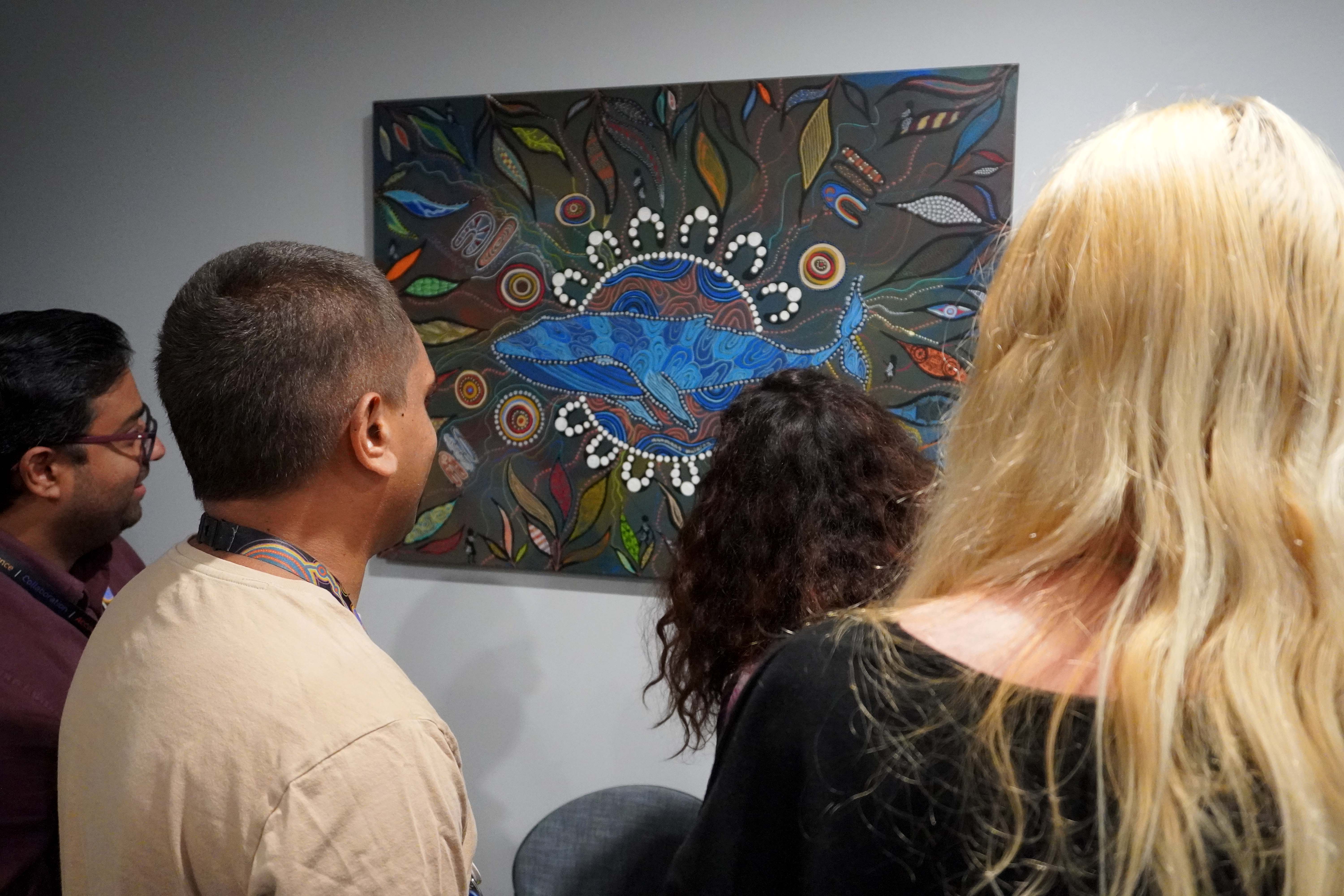 People looking at a painting hanging on a wall